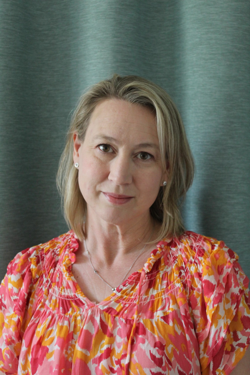 Jennie Edvardsson, Sustainable Transport Business Manager at Scania, standing in front of a blue curtain with her flower blouse.
