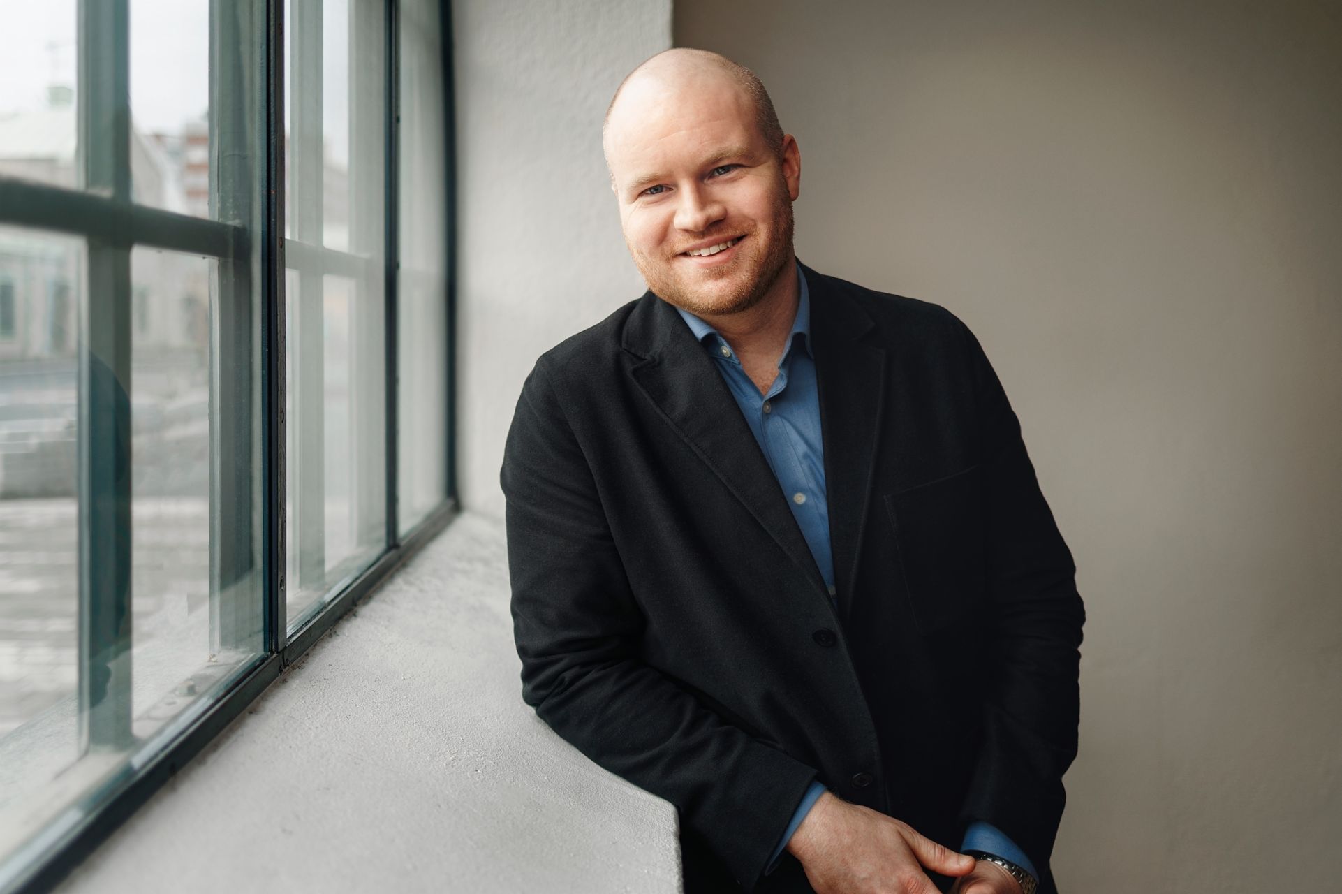 Oscar Duse, Senior Portfolio Manager bei Group Product Management, lächelt. Er trägt ein blaues Hemd und einen schwarzen Mantel. 