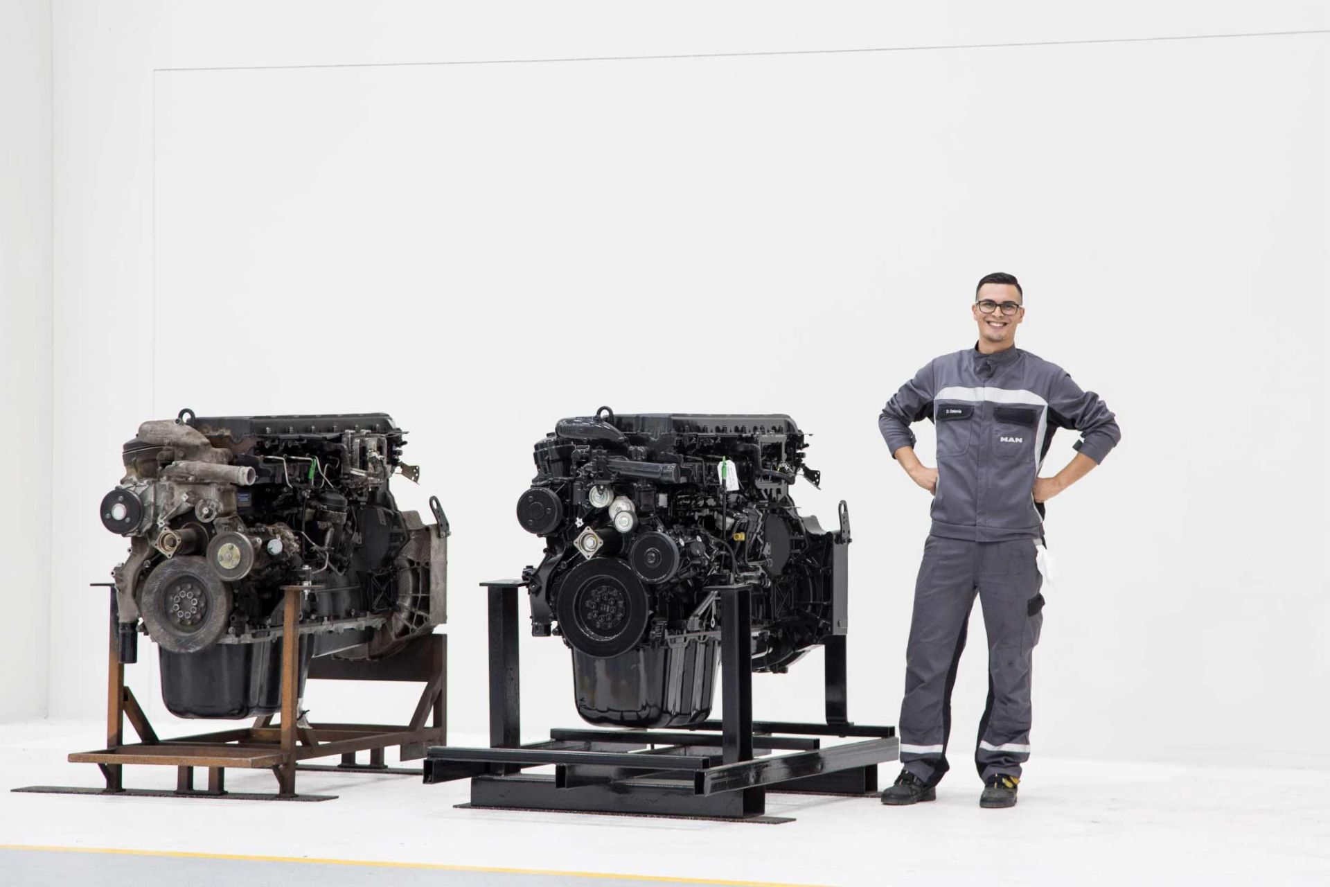 MAN employee with a used engine on the left and a remanufactured engine on the right, highlighting the before-and-after of engine reconditioning.