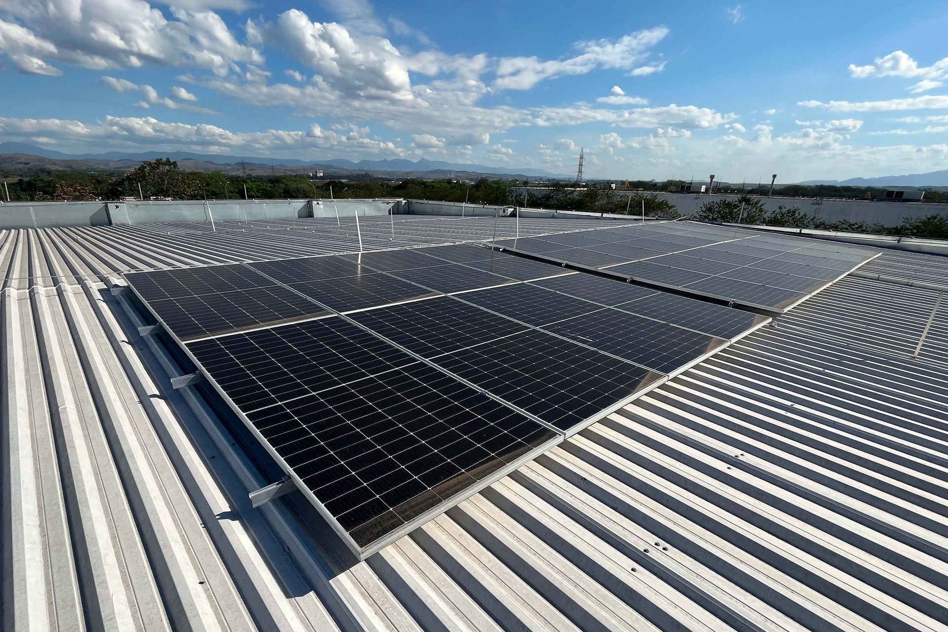 Solarmodule, installiert auf einem Metalldach unter klarem blauem Himmel, umgeben von einer malerischen Landschaft.