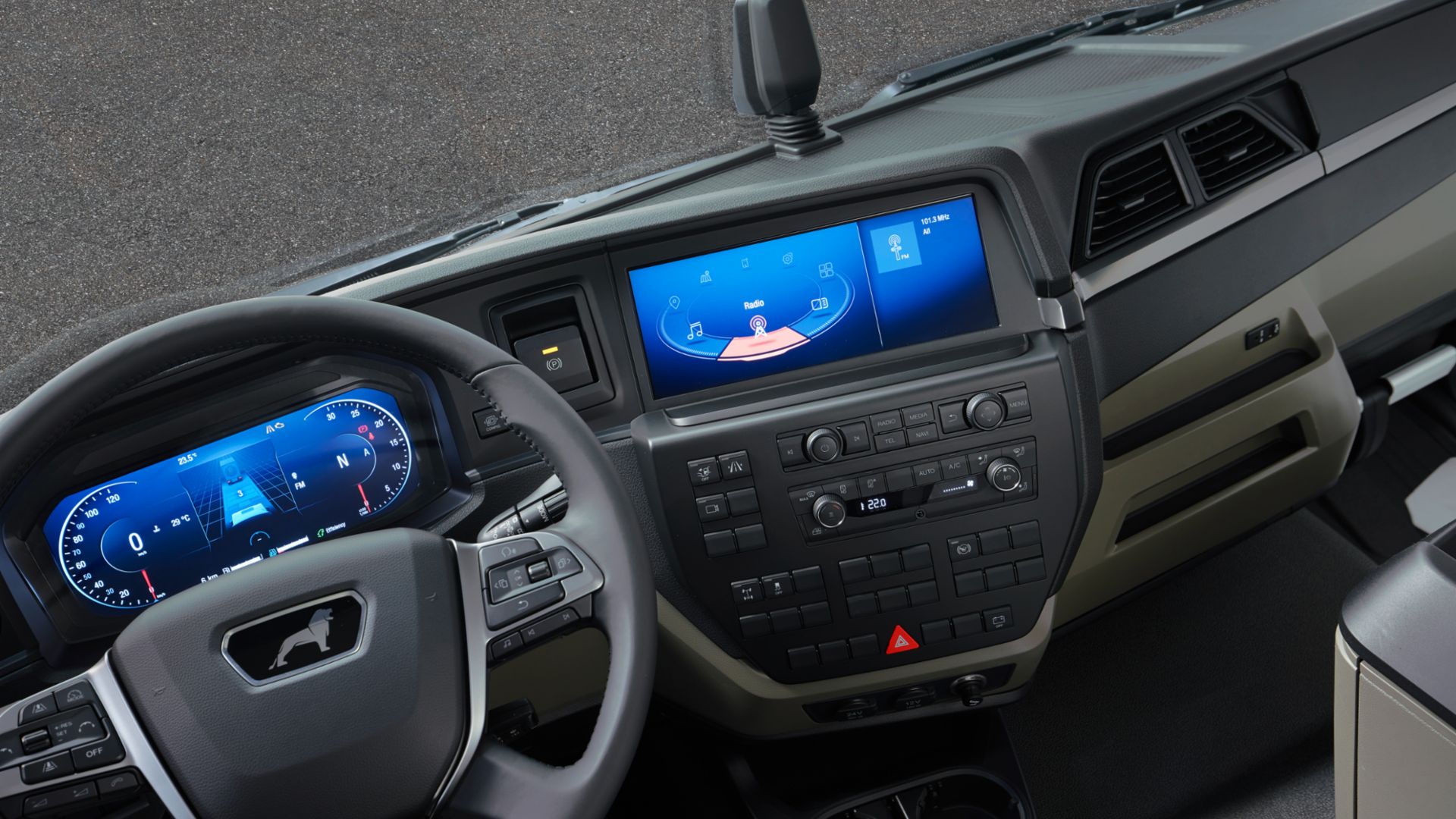 MAN vehicle interior with a steering wheel that has a screen behind showing a following distance indicator, speedometer and tachometer. Additional screen in the middle of the dashboard showing some entertainment features and buttons on the bottom.
