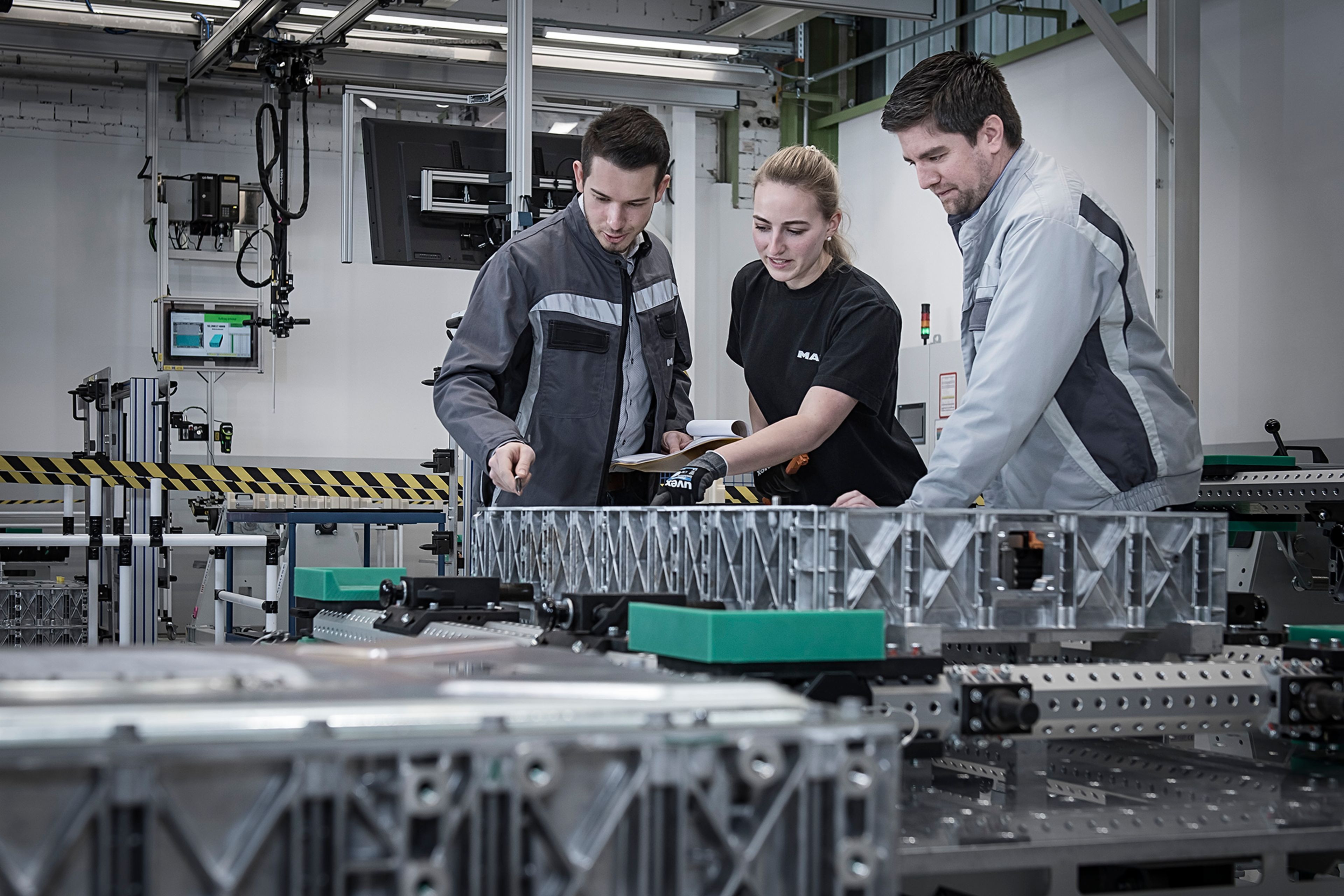Three people overseeing a MAN battery production in Nuremberg.