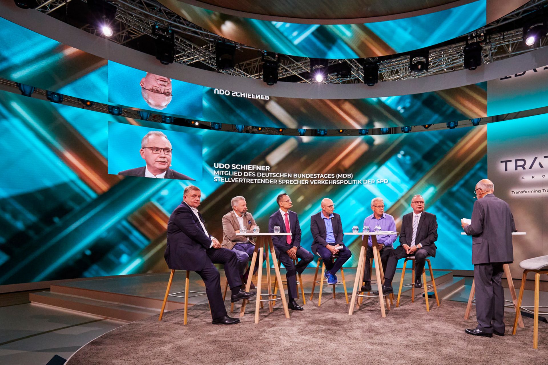 7 Männer sitzen an zwei Tischen bei einer Talkrunde bei TRATON während der IAA 2018.