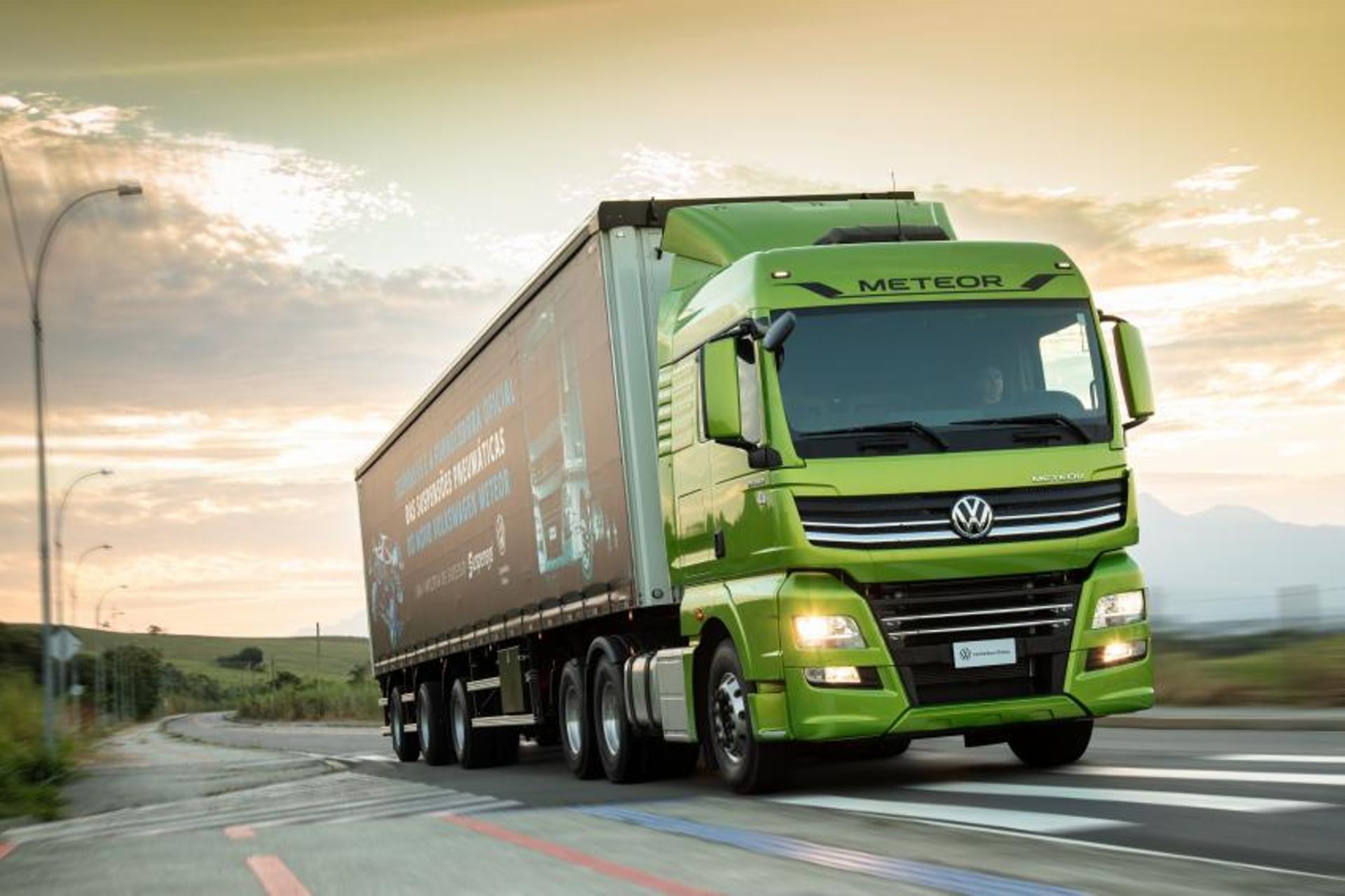 Image of a green VWCO truck driving on a street
                 