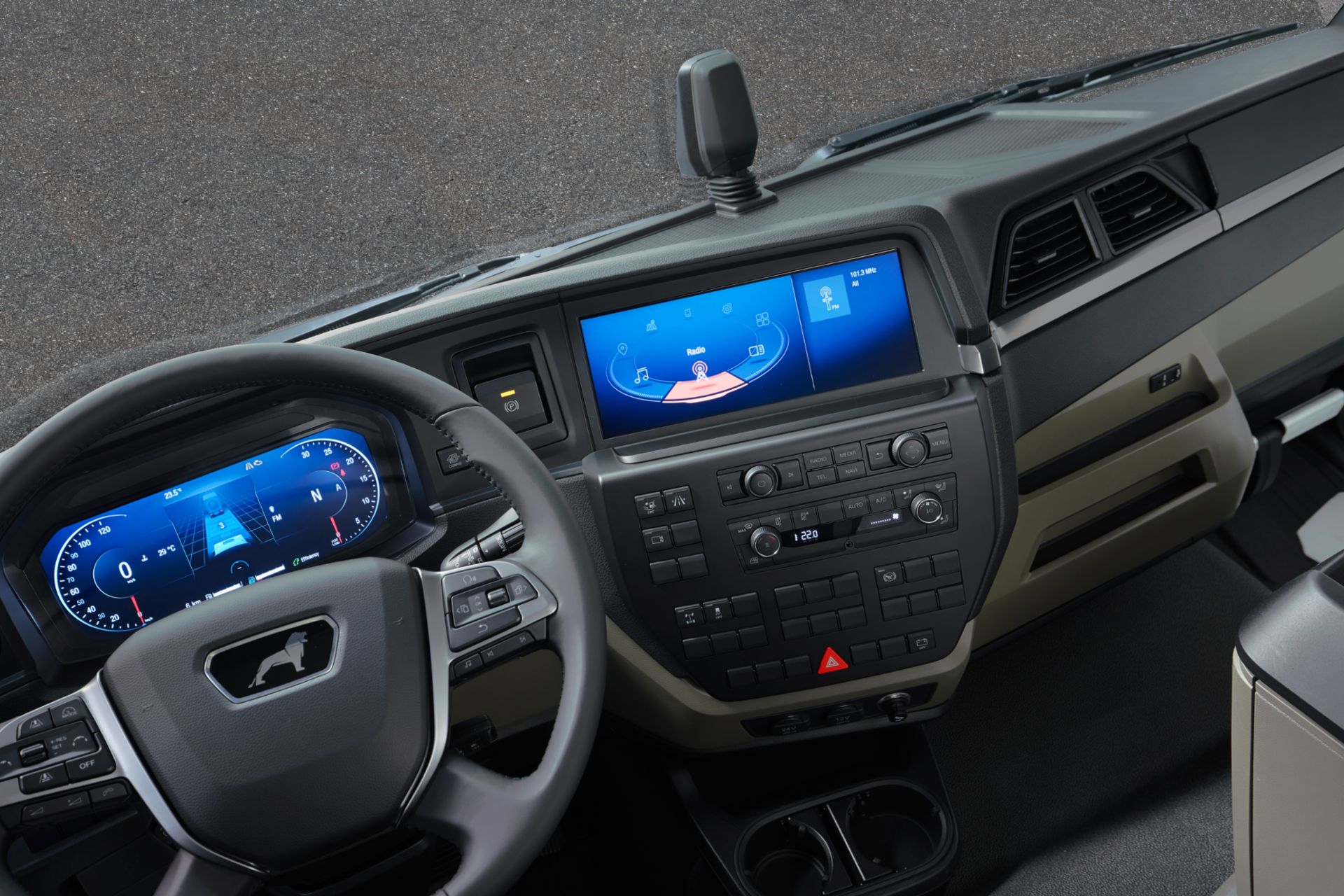 MAN vehicle interior with a steering wheel that has a screen behind showing a following distance indicator, speedometer and tachometer. Additional screen in the middle of the dashboard showing some entertainment features and buttons on the bottom.