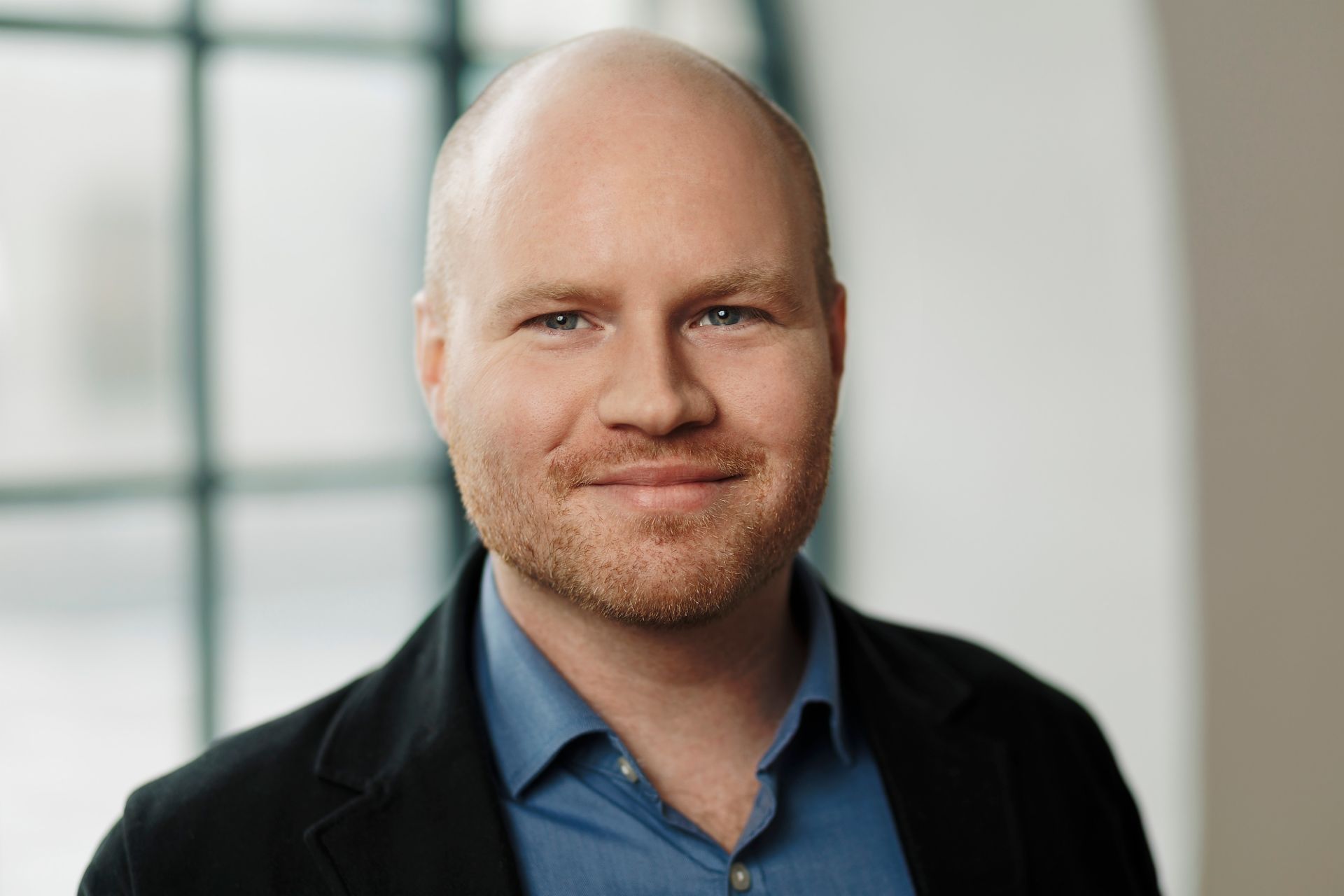 Oscar Duse, Senior Portfolio Manager bei Group Product Management, lächelt. Er trägt ein blaues Hemd und einen schwarzen Mantel. 